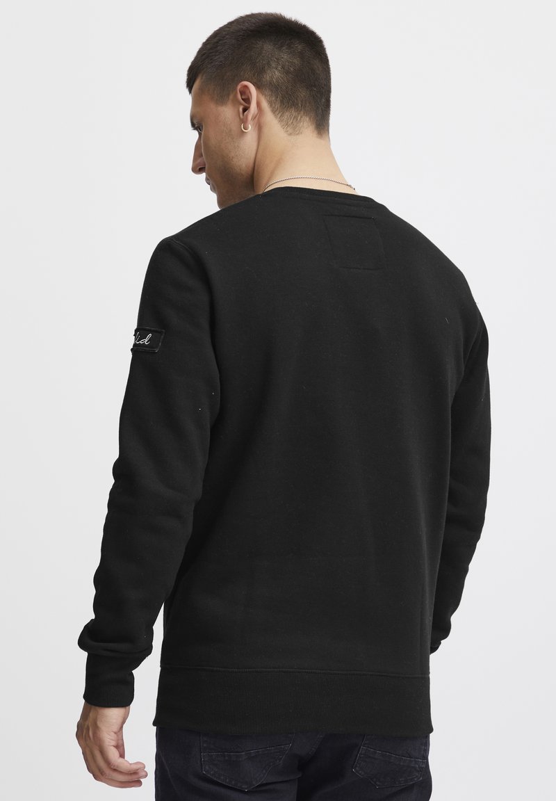 Zwarte sweatshirt met een gestructureerde afwerking, ronde halslijn, ribgebreide manchetten en tailleband. Bevat een klein label op de linkermouw.