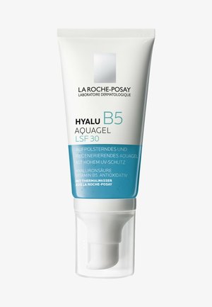 Weißes Röhrchen mit blauer Basis, ausgestattet mit einem Pumpen dispenser. Der Text umfasst "HYALU B5 AQUAGEL LSF 30". Enthält Informationen zu Hydratation und UV-Schutz.