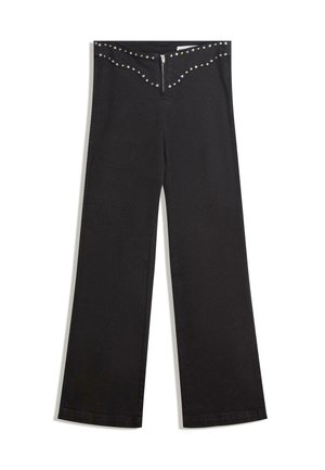 Pantalon noir à jambes larges avec une fermeture éclair, présentant un design en festons à la taille orné de clous en argent pour un détail supplémentaire.