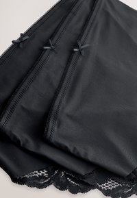 Tissu noir à texture lisse avec bordure en dentelle en bas. Trois sections ornées de petits accents de ruban noir.