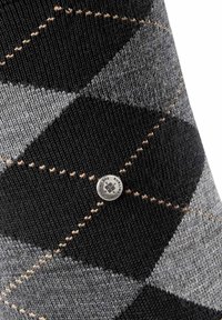 Calcetín de patrón argyle en negro y gris, hecho de tela de punto, que presenta una etiqueta de marca metálica en el costado. Detallado con acentos de costura en beige.