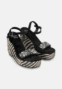 Sandali con zeppa nera in suede, con una base intrecciata a motivi, caratterizzati da una fascia decorata con strass e una fibbia alla caviglia regolabile.