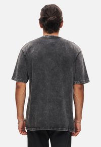 Mörkgrå överdimensionerad T-shirt med en utvikt look, korta ärmar och rullade manschetter, med rund halsringning och sömdetaljer längs nederkanten.