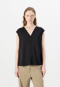 Top nero a maniche corte con scollo a V e vestibilità rilassata. Realizzato in tessuto morbido, presenta cuciture discrete lungo le spalle.