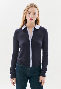 Cardigan marine avec un col boutonné bleu clair, tissu doux, design ajusté, poignets côtelés et boutons sur le devant.