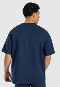 T-shirt a maniche corte di colore blu navy, realizzato in tessuto morbido simile al cotone, con una vestibilità comoda e un design semplice, caratterizzato da un collo rotondo.