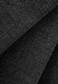 Close-up of dark gray woven fabric with diagonal folds showing textured, tightly knit fibers and soft appearance.