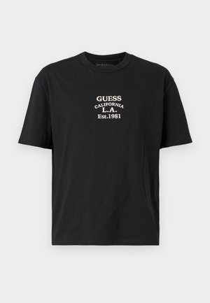 Camiseta de algodón negra con un logo impreso en blanco que dice "GUESS CALIFORNIA L.A. Est.1981" centrado en el pecho. Diseño clásico de cuello redondo.