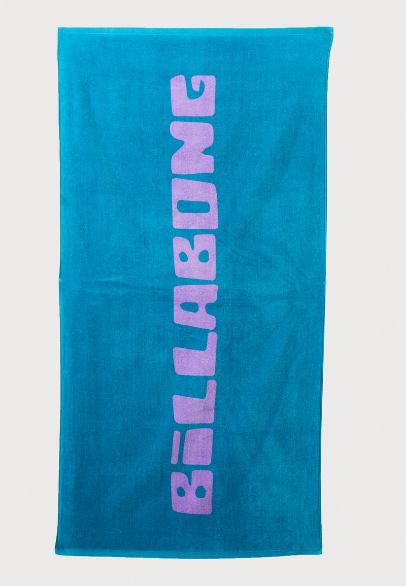 Turkis strandhåndkle laget av frotté med en vertikal lilla "BILLABONG" logo. Glatt tekstur med en lys, levende fargekontrast.