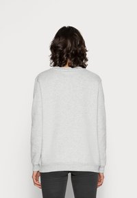Sudadera gris de manga larga, diseño de cuello redondo, textura suave y puños acanalados. Costuras visibles y un branding mínimo en la parte de atrás.