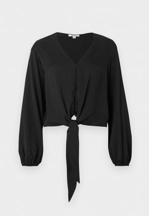 Blouse noire à manches longues avec encolure en V, boutons sur le devant, poignets élastiques et détail noué à l'ourlet avant.