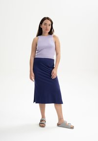 Lila mouwloze ribbeltop gecombineerd met een marineblauwe midi-rok. Model draagt grijze sandalen. Soepele stof met een lichte stretch en een zijspleet.