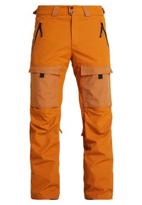 Pantalon outdoor orange avec renforts aux genoux, poches avant zippées, passants pour ceinture et fermeture à boutons-pression.