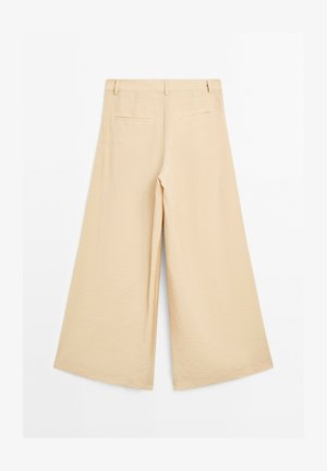 Pantaloni beige a gamba larga con una texture liscia, dotati di una vita piatta, due tasche posteriori e una vestibilità comoda.