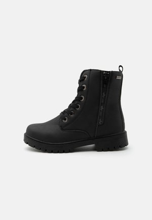 Bottine noire à lacets avec fermeture éclair latérale, œillets métalliques, languette au talon et semelle robuste sur un fond clair uni.