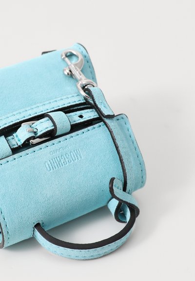 Turquoise suede wallet with black leather accents, featuring a zip closure, a handle, and a silver metal clip hardware detail.