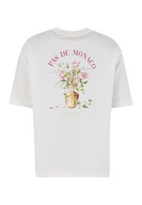Λευκό T-shirt με ανθοδέσμη σε χρυσό βάζο και κείμενο "PAS DE MONACO" και "FLORALE" στην πλάτη.