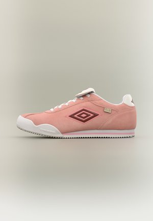 Zapatilla deportiva de ante rosa de perfil bajo con suela blanca, cordones blancos y logo burdeos de Umbro en el lateral, mostrada de perfil sobre un fondo neutro.