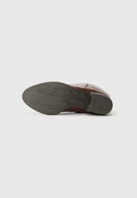 Brown shoe sole with a textured pattern, showing its flat design. The brand name "Gabot" is visible near the heel.
