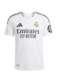 Camiseta de fútbol blanca con acentos negros, con la marca "Emirates Fly Better" y el escudo del club. Presenta un diseño de cuello en v y un tejido texturizado.