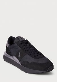 Black athletic shoe featuring a mix of textured materials, including mesh and suede, with a sleek design and logo detail on the side.