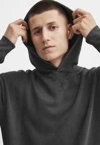 Dunkelgrauer Kapuzenpullover aus strukturiertem Stoff. Verfügt über einen gerippten Saum und Bündchen sowie ein minimalistisches Design ohne sichtbare Logos.