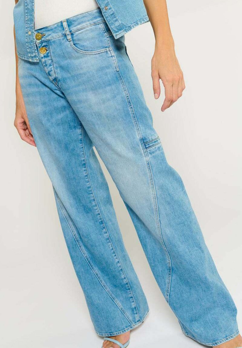 Lichtblauwe wijde jeans gemaakt van denim. Voorzien van gouden knoopsluitingen, voorzakken en een relaxte pasvorm met zichtbare stikseldetails.