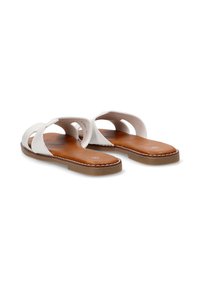 Sandalias blancas de cuero con un diseño minimalista, que presentan correas anchas y una suela contorneada marrón con detalle de costura.