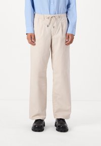 Beige, løstsiddende bukser med elastisk talje og snoretræk. Fremstillet af glat stof, med sidelommer og lige ben.