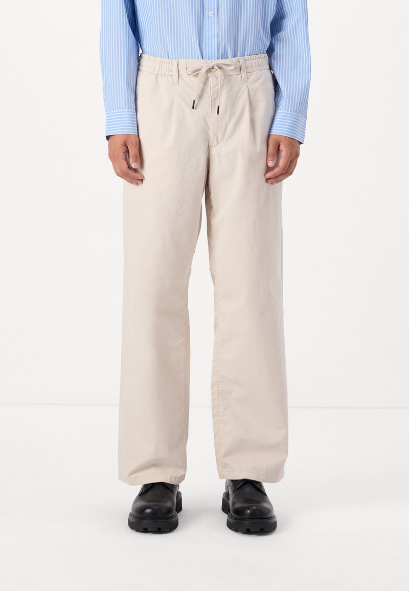 Beige, løstsiddende bukser med elastisk talje og snoretræk. Fremstillet af glat stof, med sidelommer og lige ben.