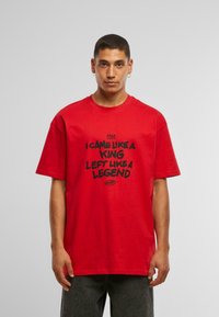 Camiseta de algodón roja con texto negro: "VINE COMO UN REY, ME FUI COMO UNA LEYENDA." Manga corta, cuello redondo, corte relajado; fondo liso.