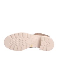 Suela de zapato de goma con un fondo blanco texturizado que presenta un patrón en zigzag y un pequeño logotipo circular. Parte superior marrón con costuras visibles.