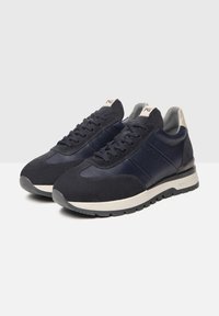 Sneakers blu navy in materiale scamosciato e in pelle, con punta rotonda, accenti testurizzati, lacci piatti e suole in gomma bianca. Branding chiaro sulla linguetta.