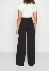 Svarta vida byxor i mjukt tyg med hög midja. Har en slät yta och minimalistisk design. Perfekta för avslappnad användning.