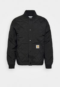 Zwarte gewatteerde jas met drukknopsluiting, geribde kraag en een klein logoviltje op het voorzakje. Lichtgewicht, gevoerd materiaal.