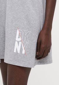 Szara bawełniana sukienka mini z logo DKNY w białym i czerwonym akcentach, charakteryzująca się luźnym krojem i miękką teksturą.
