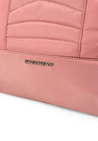 Bolsa acolchada rosa con una textura suave, que presenta el logo metálico "SKECHERS" y detalles de costura sutiles. Material duradero y ligero.