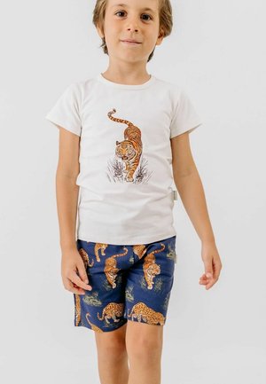 Child wearing white t-shirt with walking tiger print and navy shorts featuring tiger and leopard patterns.
