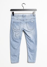 Jeans de mezclilla azul claro con un diseño ajustado, que cuentan con dos bolsillos traseros, costuras sutiles y una textura suave. Cuelga en una percha negra.