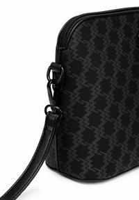 Černá texturovaná crossbody taška s geometrickým vzorem, se zipovým uzávěrem, koženým popruhem a kovovými akcenty.