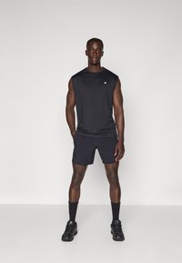 Čierny športový top bez rukávov a šortky z ľahkého materiálu. Obsahuje okrúhly výstrih a logo na ľavej strane hrude.