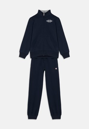 Dunkelblauer Champion-Trainingsanzug mit Reißverschlussjacke, die ein Logo auf der Brust trägt, und passender Jogginghose mit Logo auf dem linken Oberschenkel.
