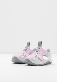 Sandali per bambini rosa e grigi con ritagli traspiranti e una suola grigia texturizzata. Include linguette grigie per una facile calzata.