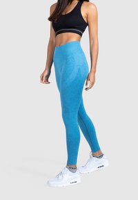 Leggings blu heathered realizzati in tessuto stretchy, design a vita alta, abbinati a un crop top nero e sneakers bianche.
