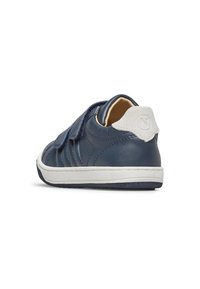 Chaussure en cuir bleu marine avec une semelle en caoutchouc blanc, une sangle Velcro et des accents texturés sur le dessus. Présente un onglet de talon en daim avec logo.