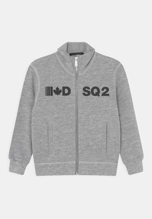Sweat-shirt zippé gris en tissu doux avec un col haut. Il présente des graphiques noirs : un drapeau, un "D" et "SQ2", ainsi que deux poches avant.