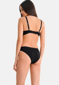 Ensemble de bikini noir avec un design simple. Le haut a des bretelles ajustables et une fermeture à crochet, tandis que le bas présente une texture lisse.