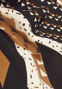 Látka s tmavým pozadím a geometrickými vzory v bílé a hnědých odstínech, vykazující hladkou texturu a jemné splývání.