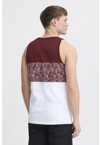 Burgunderfarbener und weißer ärmelloser Tanktop mit einem strukturierten Strickdesign im oberen Bereich; glattes weißes Material im unteren Bereich.