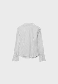 Chemise blanche à manches longues avec des rayures verticales noires, poignets boutonnés et col pointu, vue de dos sur un fond uni.